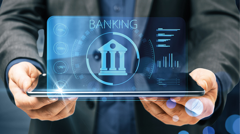 A person in a suit holds a tablet displaying a digital banking interface. The screen shows a bank icon, numerical data, and graphs, emphasizing modern financial technology and data analysis in banking services.