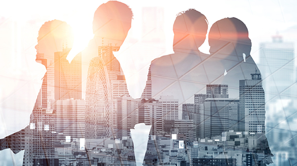 Silhouettes of four people stand against a backdrop of a city skyline. The image conveys a theme of collaboration and innovation, with sunlight illuminating the scene, symbolizing new ideas and opportunities in an urban environment.