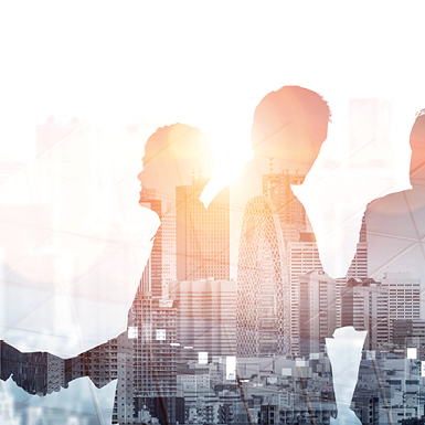 Silhouettes of three individuals stand against a bright backdrop featuring a city skyline. The image conveys a sense of collaboration and urban environment, symbolizing teamwork and progress in a modern setting.